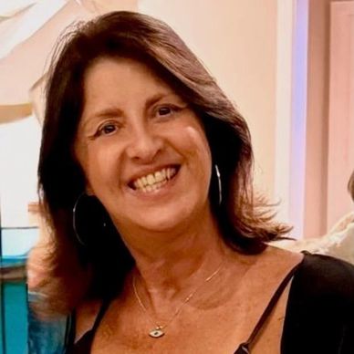Mulher sorridente com cabelo castanho e brincos de argola.