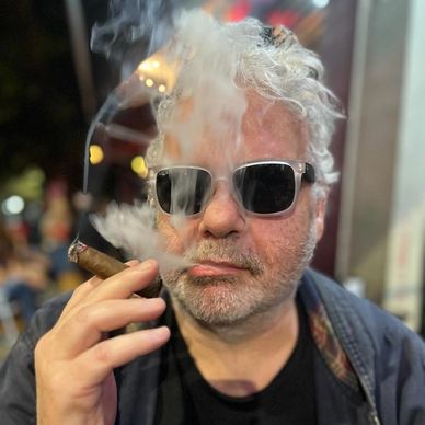 Homem usando óculos escuros fumando um charuto.