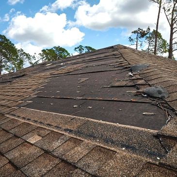Damaged roof with missing shingles and exposed underlayment.