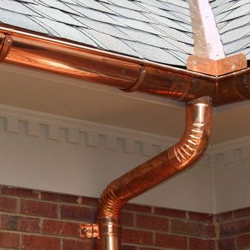 Shiny copper gutter system on a house roof corner.