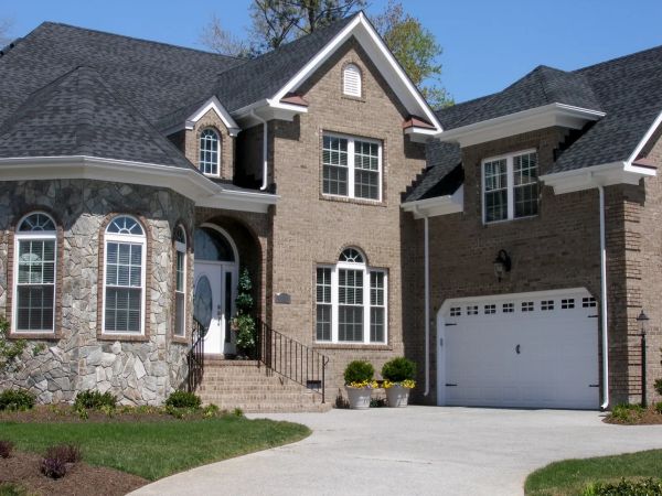 Elegant brick and stone house with large windows and a spacious driveway.