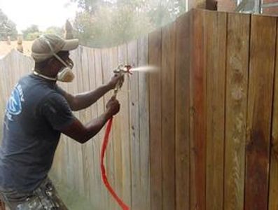 Painter in Richmond, Virginia applying Ready Seal water sealant using a spray-gun to new fencing.
