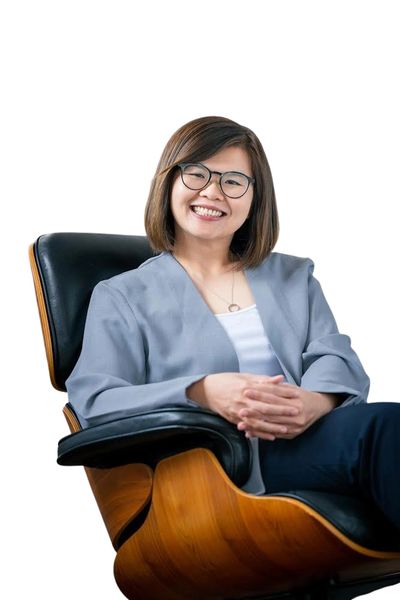 Smiling woman with glasses sitting comfortably in a modern chair.