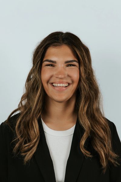 Smiling young woman with wavy hair in black blazer.