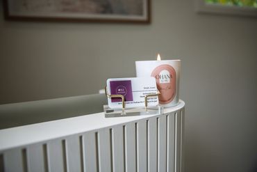 A lit candle and business cards on a white radiator in a cozy room.