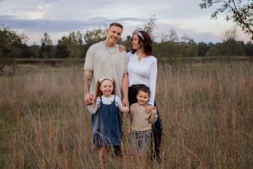 Smiling family with two kids in a field.