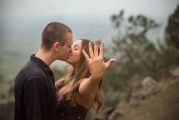 Couple kissing with engagement ring in focus.