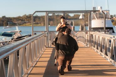A man proposing to a woman on a dock.