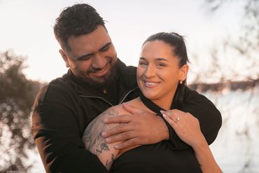 Couple smiling and embracing outdoors.