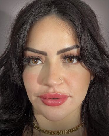 Close-up of a woman with dark hair, brown eyes, and glossy lips.