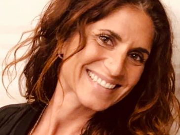 Smiling woman with curly brown hair and bright eyes.