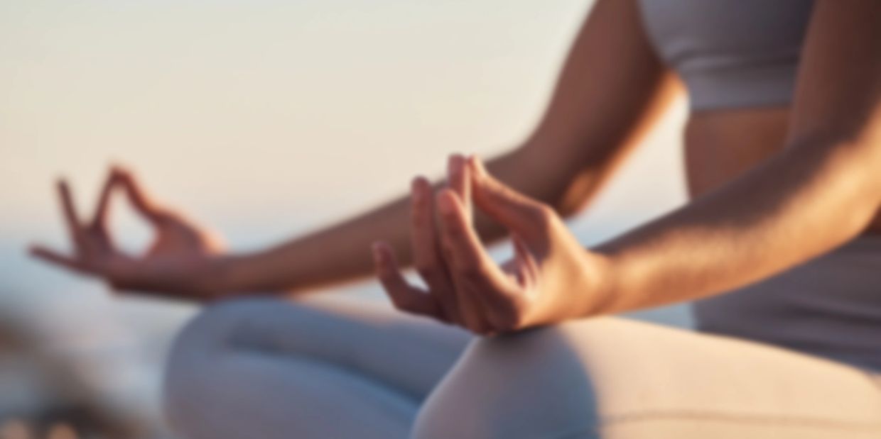 Person meditating with hands in a mudra gesture, sitting cross-legged.
