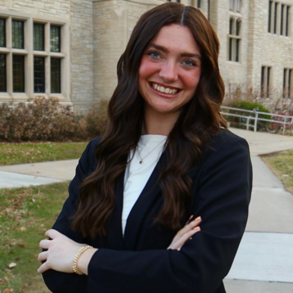 Young woman smiling confidently outdoors in professional attire.