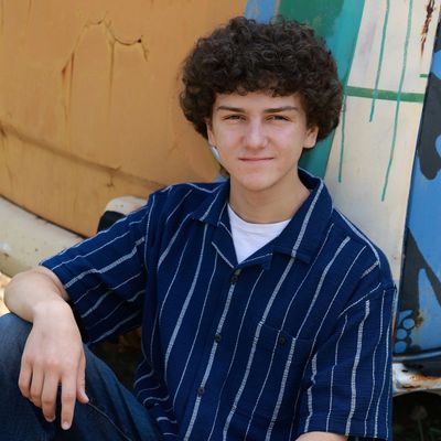 Young man sitting casually, smiling slightly.