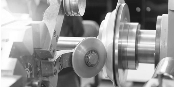 Metal spinning machine in action, shaping a piece of sheet metal into a desired shape