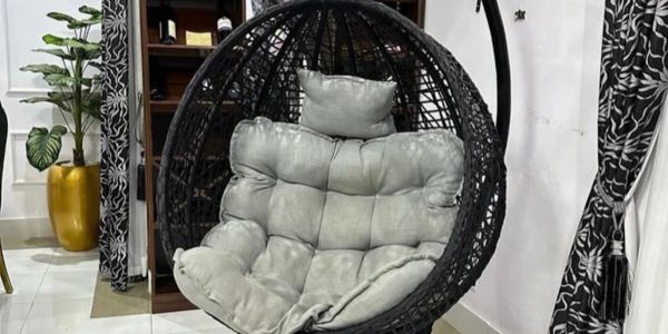 Black hanging egg chair with gray cushions in a modern living room.