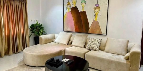 Modern beige sectional sofa with colorful abstract art and black coffee table.