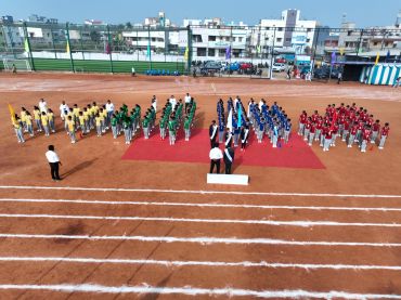 Students standing in four organized groups on a sports field.