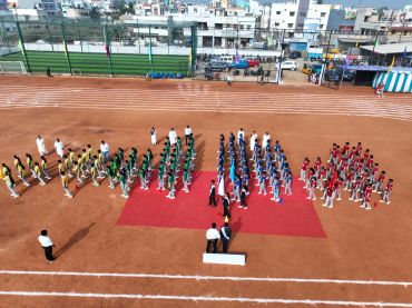 Students in sports uniforms lined up on an outdoor track ground.
