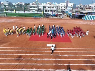 Students in colored uniforms standing in formation on a sports ground.
