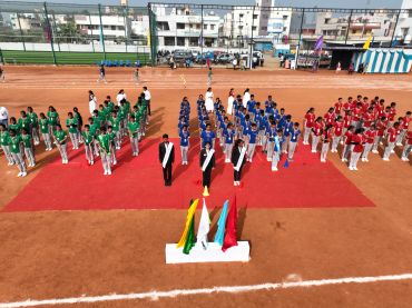 Students lined up in colorful uniforms on a sports ground for an event.