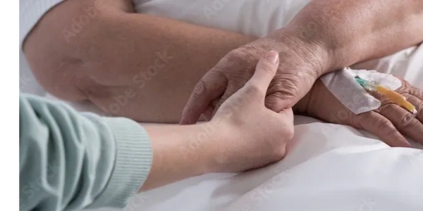 Someone holding hands with a patient in a hospital bed 