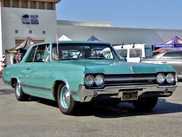 Classic turquoise 1960s muscle car parked at a car show.
