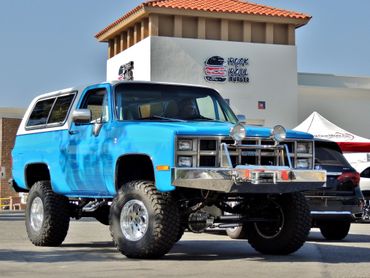 Blue lifted off-road truck parked in front of a building.