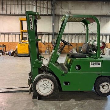 A green Clark forklift inside a warehouse.
