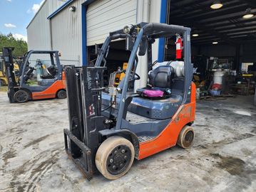 Orange and black forklift parked outside a warehouse.
