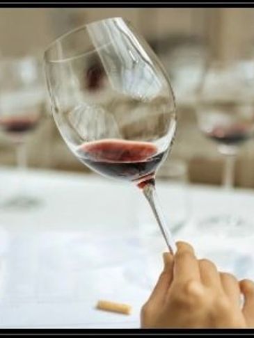 Hand holding a tilted wine glass with red wine.