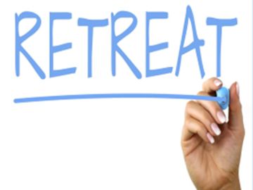 Hand writing the word 'RETREAT' in blue.