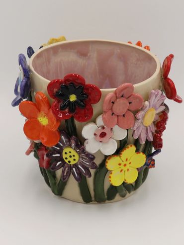 Colorful ceramic flower-decorated pot with various vibrant blossoms.