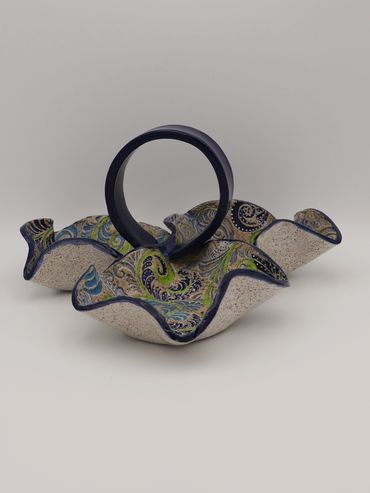 Decorative ceramic basket with intricate blue and green patterns and a dark handle.