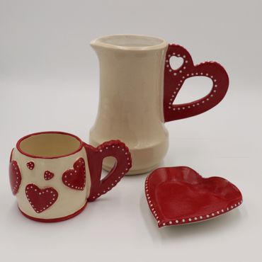 Ceramic set with heart-themed designs in red and white.