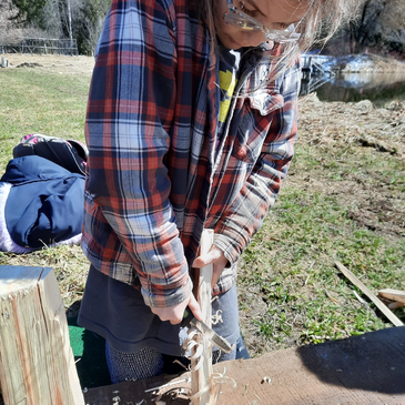 child practicing feather sticking to create kindling