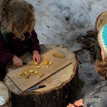child practicing using a knife with adult supervision