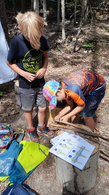 children practicing tripod lashing to build tipi