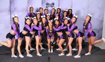 Cheerleading team posing in purple and black uniforms with white bows.