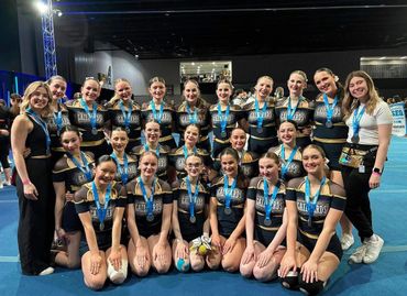 A cheerleading team posing proudly with their medals and trophies.