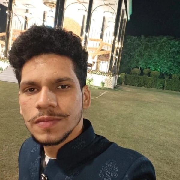 Young man with a mustache taking a selfie outdoors at night.