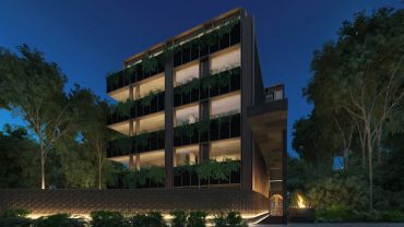 Edificio moderno iluminado de noche rodeado de árboles.