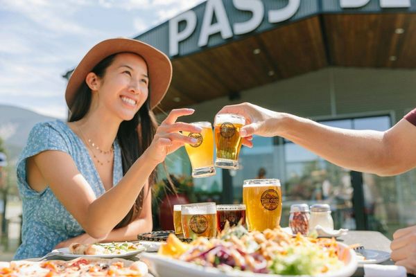 Two people enjoying a cheerful beer toast outdoors at a restaurant.