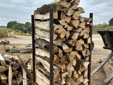 Long firewood logs in a metal container on a farm.