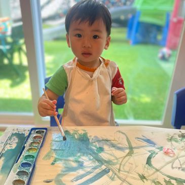 Closeup shot of toddler painting on a sheet