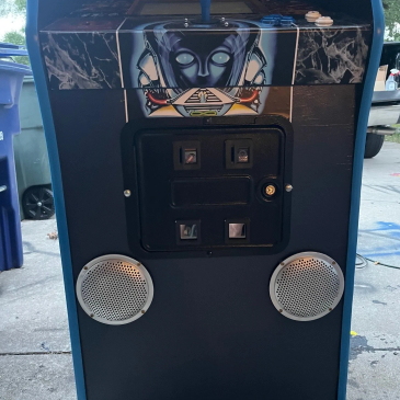 Front panel of a blue arcade machine with distinct artwork and speakers.