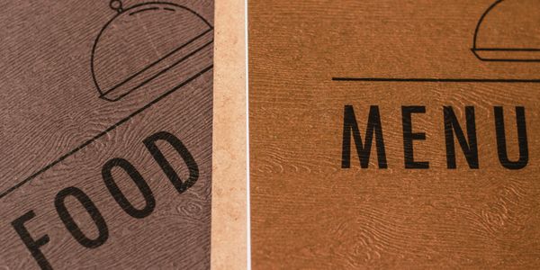 Close-up of two textured restaurant menu covers side by side.