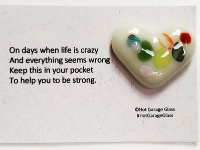 A heart-shaped glass piece with a motivational quote about strength during tough times.