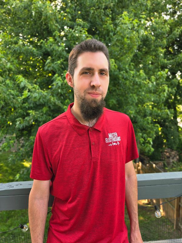 Man in a red polo shirt standing outdoors.