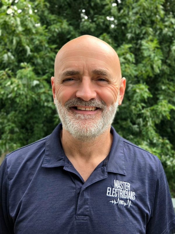 Smiling bald man with white beard in a navy shirt.